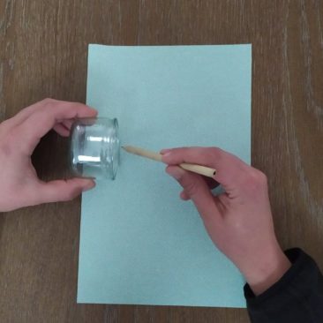 Repérer sur la feuille de papier, avec un crayon, la hauteur du pot de yaourt. Tracer une ligne du haut au bas de la feuille.
